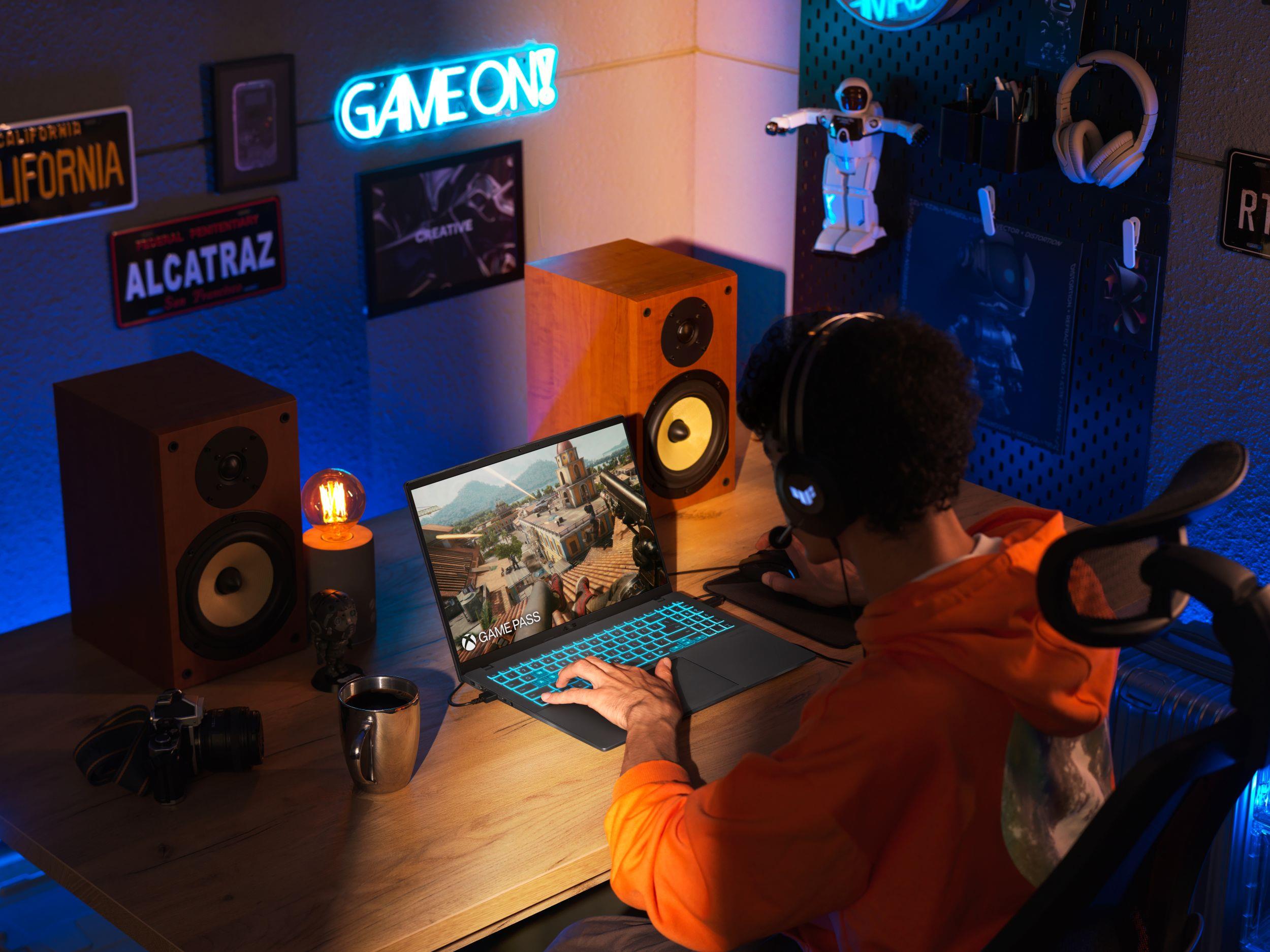 A person playing games in a dimly lit game room on an ASUS V16 laptop.